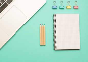 Workspace with laptop, notebook, and pen on mint background top view