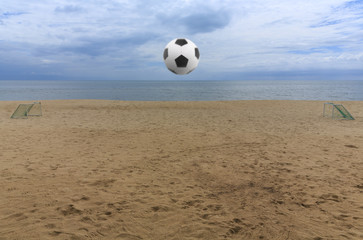 The goal with soccer ball flying through the air above on sand beach field