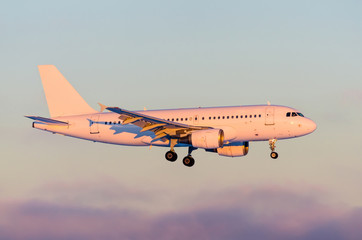 Commercial airplane landing in dramatic sunset light.