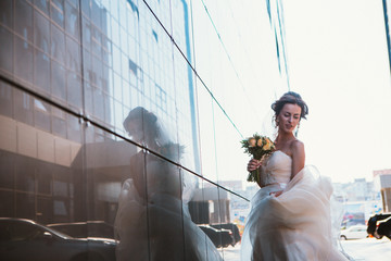 Obraz na płótnie Canvas Bride and bouquet on backround mirror buildings.