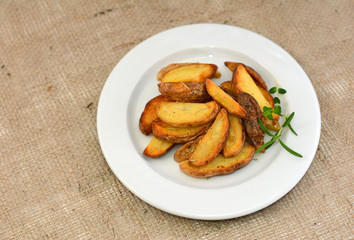 Fried potato wedges with herbs on plate.
