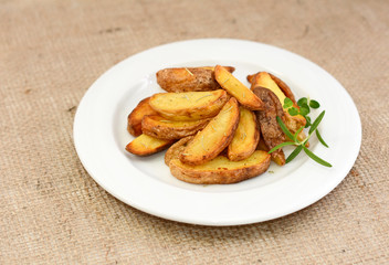 Fried potato wedges with herbs on plate.