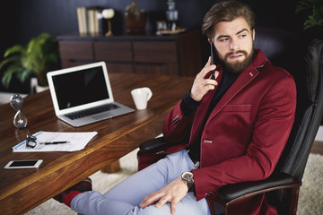 Business person talking by phone at home office