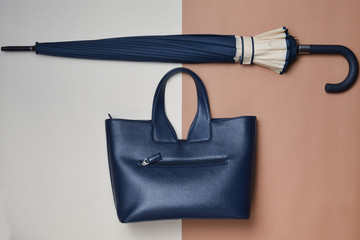 Women's seasonal accessories. Female leather bag and umbrella on a beige brown paper background....