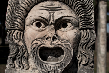 Fototapeta na wymiar Marble Mask decoration in Ostia Antica theatre. Ancient Rome 1st century mask in the proscenium of Ostia antica, part of architectonic decoration