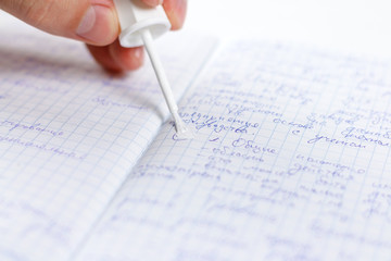 Hand holding white corrector for text in the notebook. Causes concealer on handwritten text....