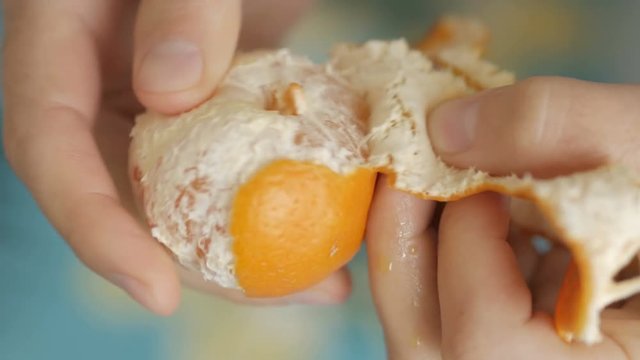 People peel a tangerine peel. Hands of man peel mandarin close up.