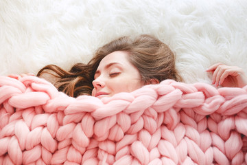 Young woman sleeping under warm peach color throw blanket
