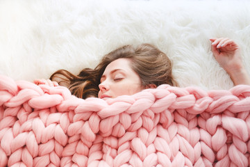 Young woman sleeping under warm peach color throw blanket