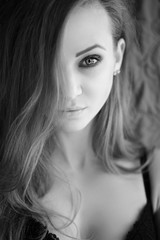 Naklejka premium Portrait of a beautiful young woman with long hair looking at camera. Black and white photo.