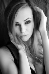 Naklejka premium Portrait of a sexy young woman with long hair on a dark background. Black and white photo.