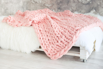 Fototapeta na wymiar Large knitted pink throw blanket for loft apartment.