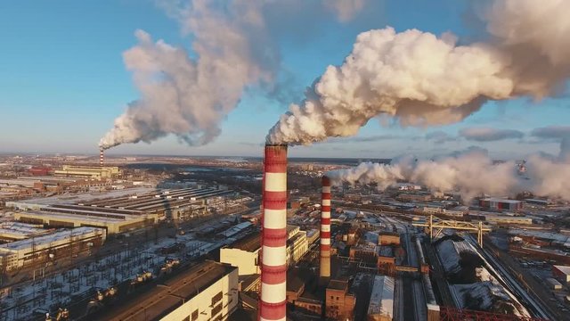 Industrial zone with a large red and white pipe thick white smoke is poured from the factory pipe in contrast to the sun. Pollution of the environment: a pipe with smoke. Aerial view