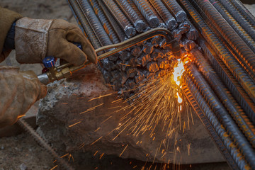 Gas cutting of metal fittings. Working gloves. Sparks.