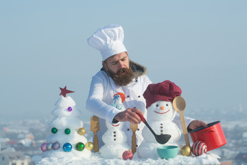 Cook, snowmen and snow xmas tree on blue sky
