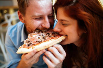 Couple sharing pizza and eating