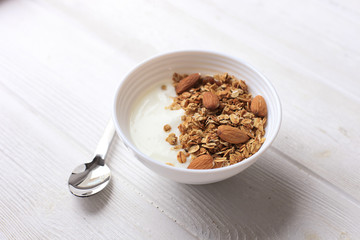 Bowl of whole grain muesli with yogurt on white wooden background, top view