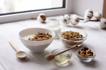 Homemade healthy granola or muesli with yogurt on white wooden background