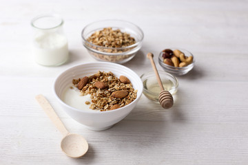 Homemade healthy granola or muesli with yogurt on white wooden background