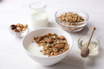 Homemade healthy granola or muesli with yogurt on white wooden background