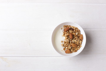 Fototapeta na wymiar Bowl of whole grain muesli with yogurt on white background, top view