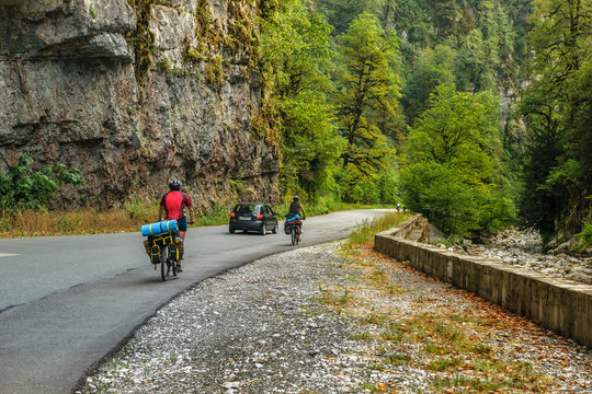 Bicyclists on asphalt road through gorge along Bzyb river near Ritsa lake in Abkhazia