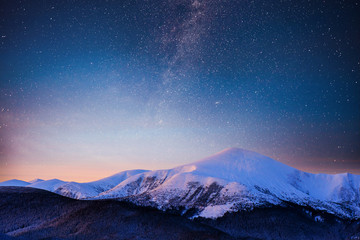 Beautiful winter landscape in the Carpathian mountains. Vibrant night sky with stars and nebula and...