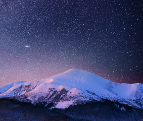Naklejka na ściany i meble Beautiful winter landscape in the Carpathian mountains. Vibrant night sky with stars and nebula and galaxy. Deep sky astrophoto