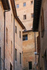 Fototapeta na wymiar Urbino, Italy - August 9, 2017: architectural elements of a building in the old town of Urbino. Red brick and windows with shutters