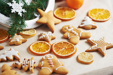 Christmas gingerbread cookies and dried orange and spices on white table. Chairs Christmas trees, cones and Christmas decorations