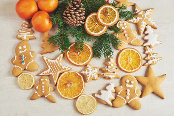 Fototapeta na wymiar Christmas gingerbread cookies and dried orange and spices on white table. Chairs Christmas trees, cones and Christmas decorations