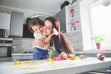 Happy family in the kitchen. Holiday food concept. Mother and daughter preparing the dough, bake cookies. Happy family in making cookies at home. Homemade food and little helper