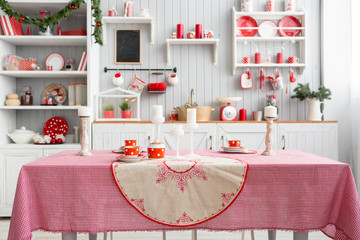 Interior light grey kitchen and red christmas decor. Preparing lunch at home on the kitchen concept. Focus on table