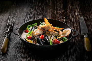 Seafood and rice noodles in cream sauce. Healthy meal made of sea bass fish, mussels, crab meat and other seafood with tomato and rice noodles.