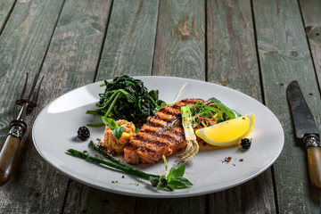 Delicious grilled salmon fish steak with vegetable salad. Healthy meal for lunch made of seafood fish and vegetables on a wooden table.