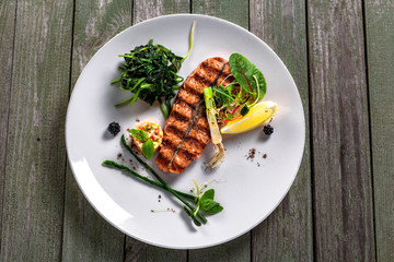 Delicious grilled salmon fish steak with vegetable salad. Healthy meal made of seafood fish and vegetables on a table. Top view.