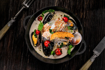 Sea bass fish fillet with mussels, crab meat and cockles with vegetables, cream sauce and rice noodles. Healthy Asian seafood meal on a table. Top view.