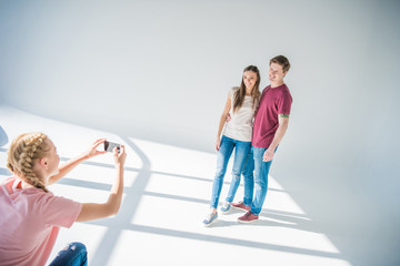 Naklejka premium girl photographing couple with smartphone