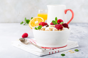 Healthy breakfast with oatmeal granola, berries and yogurt on light gray background. Copy space.