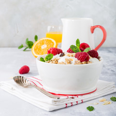 Oat granola with berries and yoghurt on light gray background. Copy space. Healthy breakfast concept.