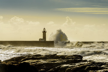 Landscape seascape lighthouse battered by huge waves on Atlantic Ocean with blue green skies and...