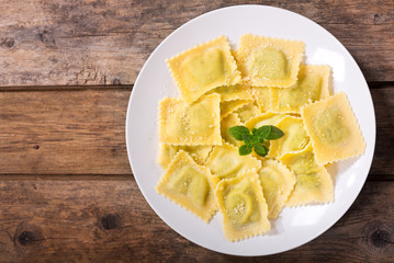 plate of ravioli with basil on wooden table