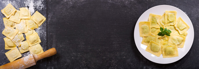 plate of ravioli with basil on dark background