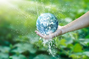 Water pouring on planet earth placed on human hand for saving resources and heal the world...