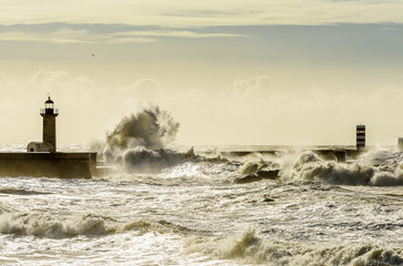 Landscape seascape lighthouse battered by huge waves on Atlantic Ocean with blue green skies and...