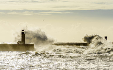 Landscape seascape lighthouse battered by huge waves on Atlantic Ocean with blue green skies and...