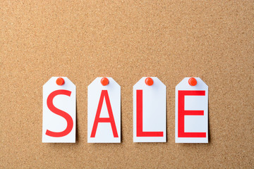 Tags with the word SALE pinned to a cork Board
