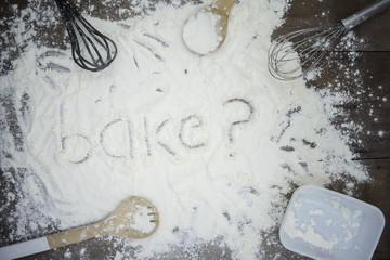 Top view of cooking table with word 'bake?' written on the flour. 