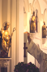 The priest lights the candle at the Catholic Church