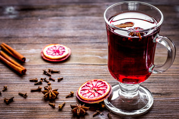 mulled wine with spices in cup on wooden background